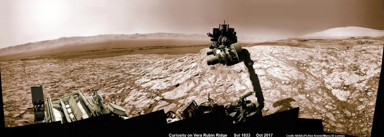 美国宇航局的好奇号火星车举起机械臂，钻头指向天空，探索盖尔陨石坑内夏普山脚下的维拉鲁宾山脊——背景是远处的陨石坑边缘。 这张 Navcam 相机马赛克由 2017 年 10 月 2 日在 Sol 1833 拍摄的原始图像拼接而成，并已着色。 图片来源：NASA/JPL/Ken Kramer/kenkremer.com/Marco DiLorenzo。